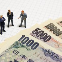 お金の横で話し合うビジネスマン